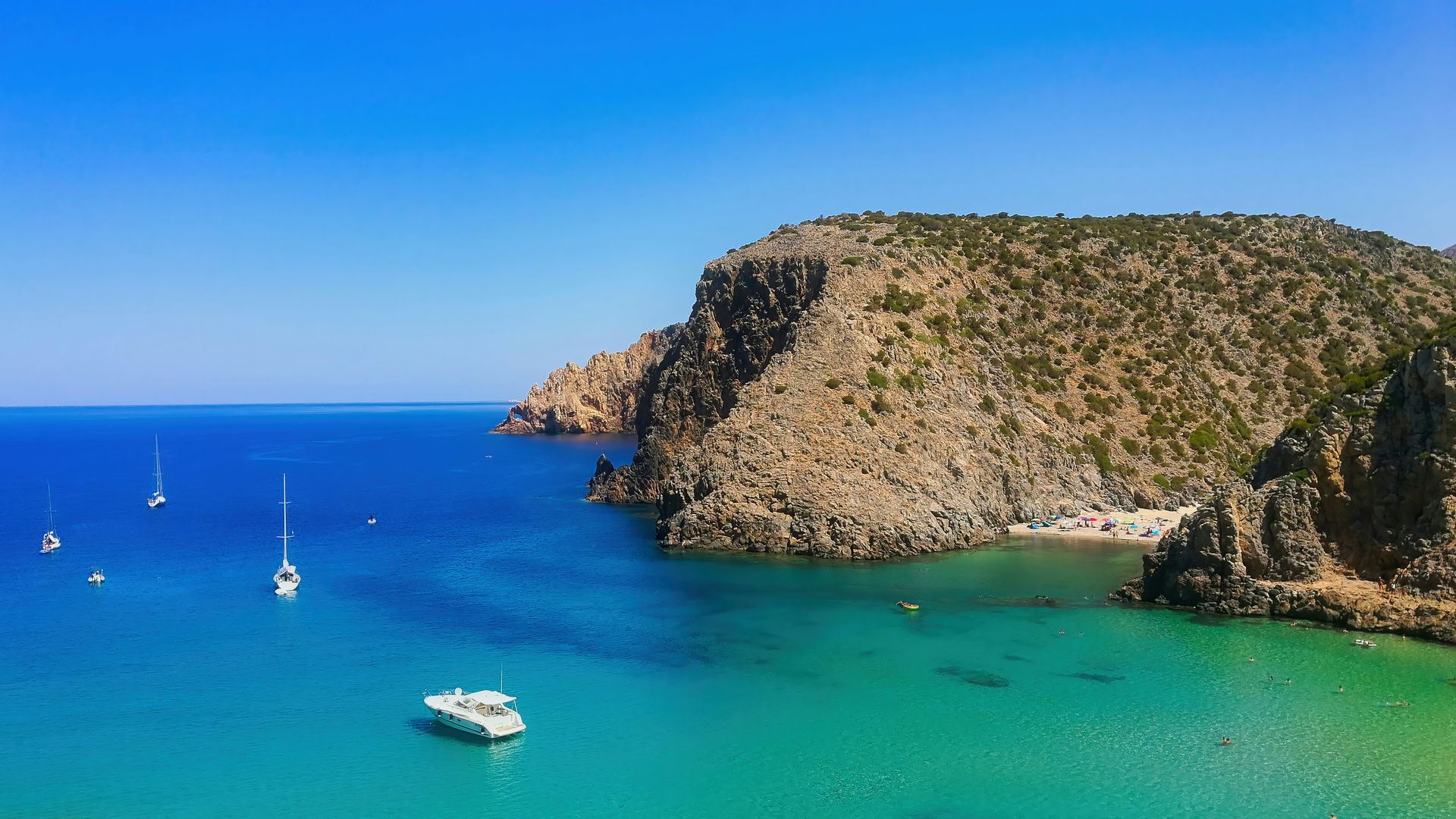 Des falaises calcaires plongent dans la mer à Cala Gonone, au pied desquelles s'étend une plage déserte.