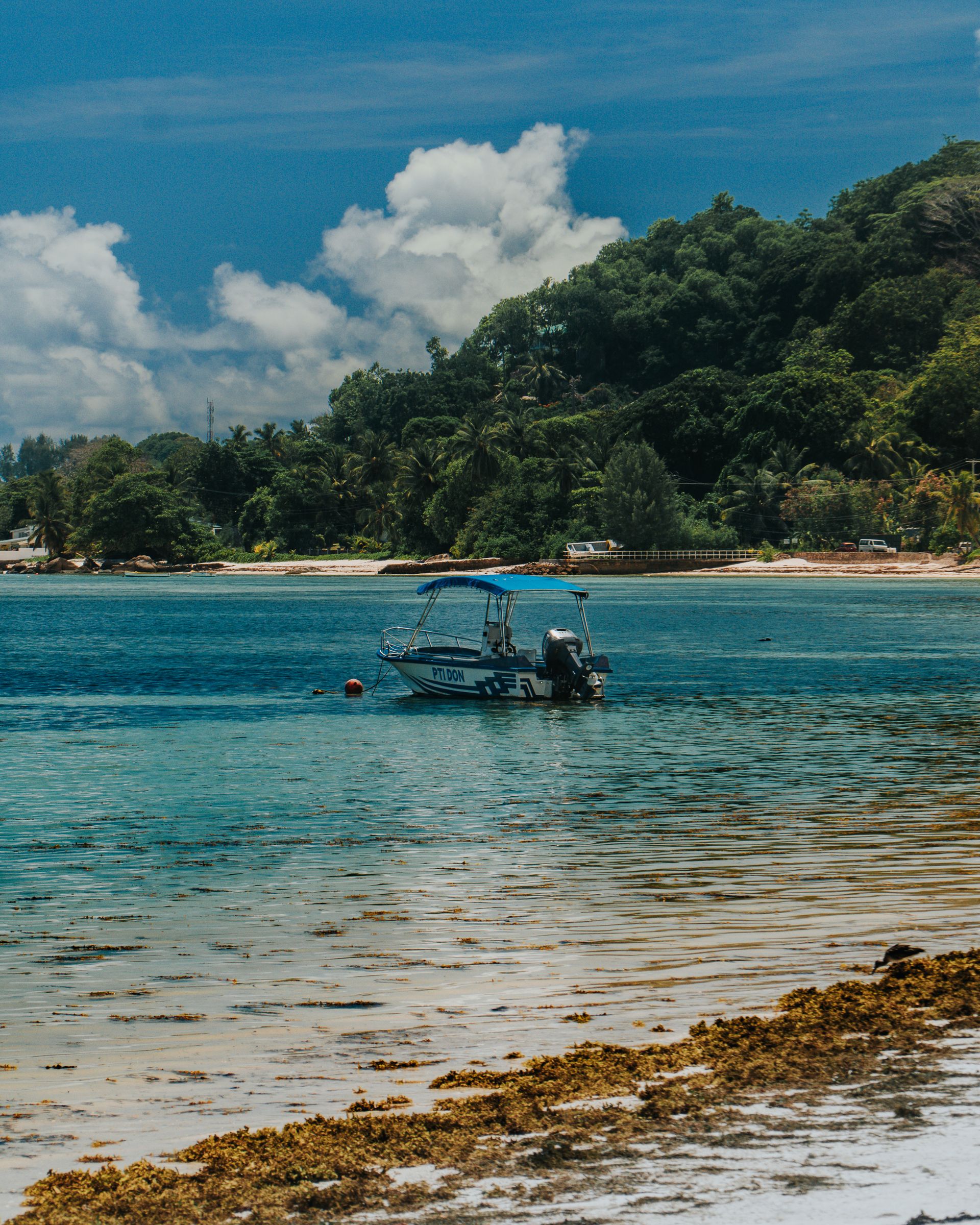Un petit bateau de pêche file à contre-jour le long d'une île montagneuse, seul sur l'eau.