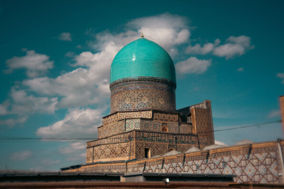 Turkooizen koepel van een madrasa tegen een strakblauwe hemel