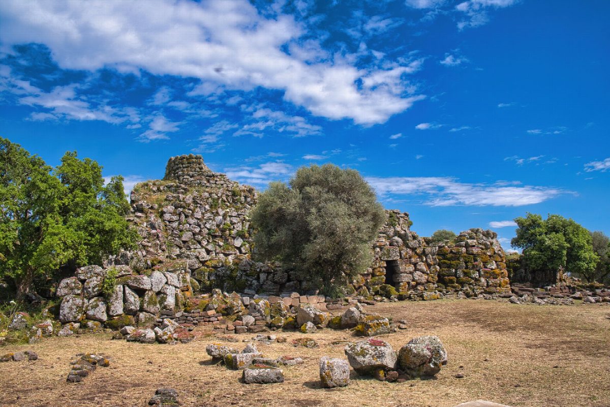 Nuraghe in droog gras met granieten heuvels op de achtergrond