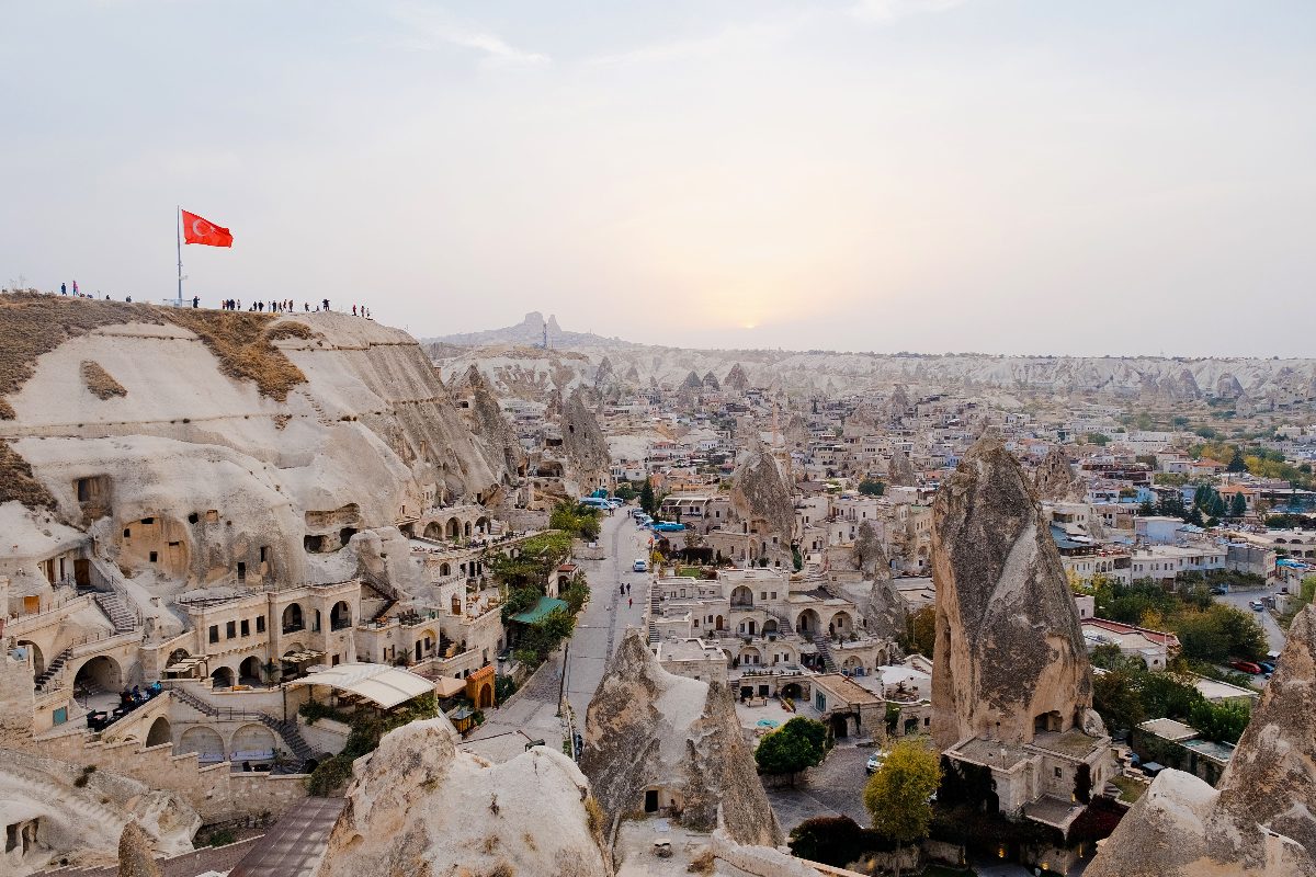 Grottenwoning in Cappadocië bij ochtendlicht, met tarwevelden van het Anatolisch plateau op de achtergrond